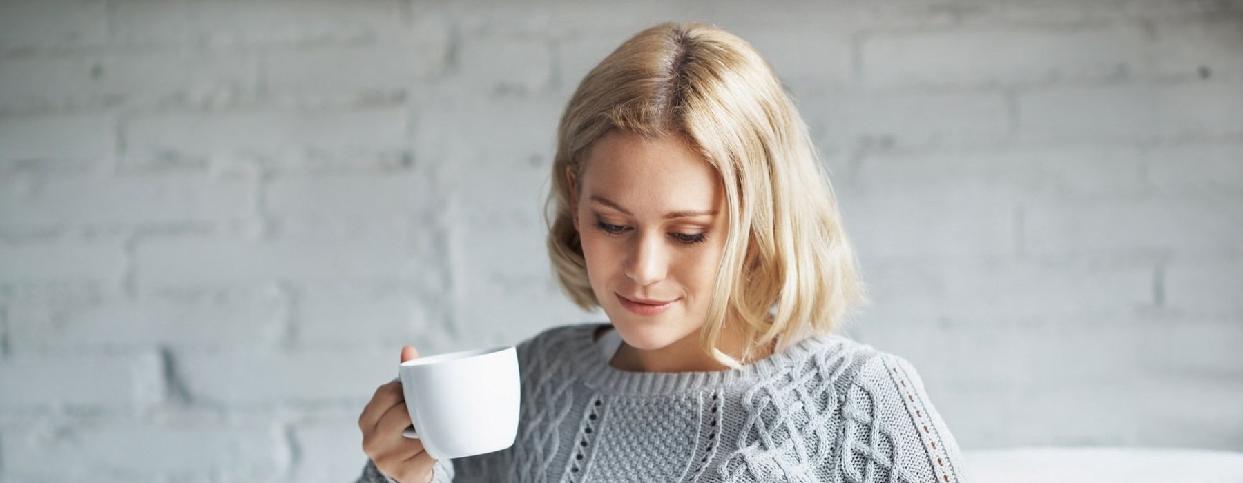 a woman holding a coffee cup looking at a tablet